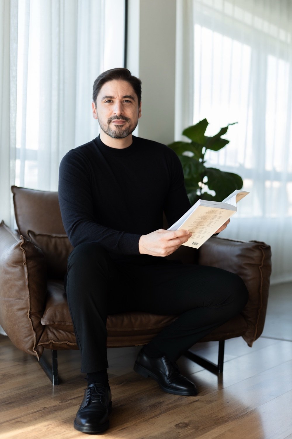 Tiago Amorim seated in an armchair, holding an open notebook